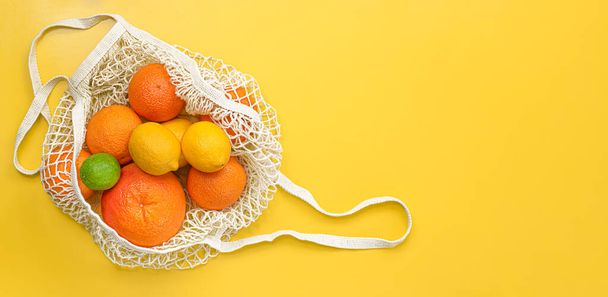 frutas frescas en una bolsa reutilizable sobre un fondo amarillo. concepto de cero residuos - Foto, Imagen
