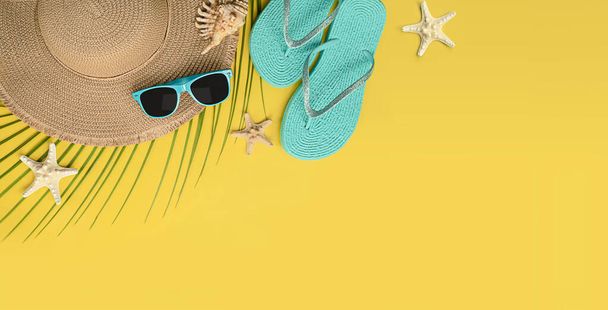 zonnehoed, teenslippers, zonnebril en schelp met zeester op gele achtergrond - Foto, afbeelding