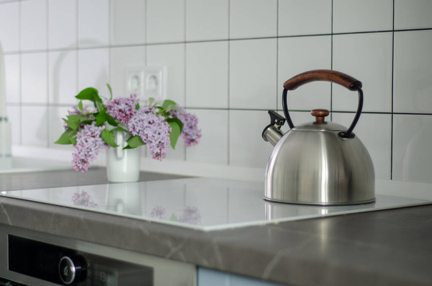 Chaleira de aço na cozinha moderna com fogão de indução
 - Foto, Imagem
