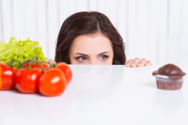 Женщина выбирает овощи или кексы
 - Фото, изображение