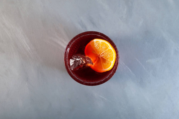 Glass of Alcohol cocktail Negroni Americano with orange and ice cubes, top view. Selective focus, copy space. - 写真・画像