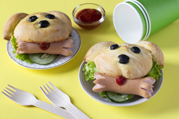 Sandwiches en forma de perro con una salchicha sobre fondo amarillo. Idea de cocina para niños - Foto, imagen
