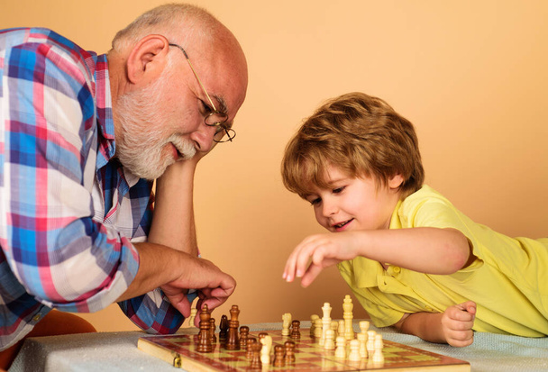 Child boy developing chess strategy. Grandfather and grandson playing chess. Brain development and logic concept. - Photo, image