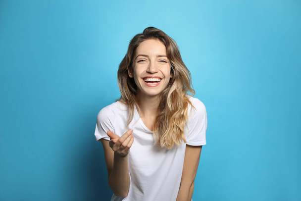 Cheerful young woman laughing on light blue background - Zdjęcie, obraz
