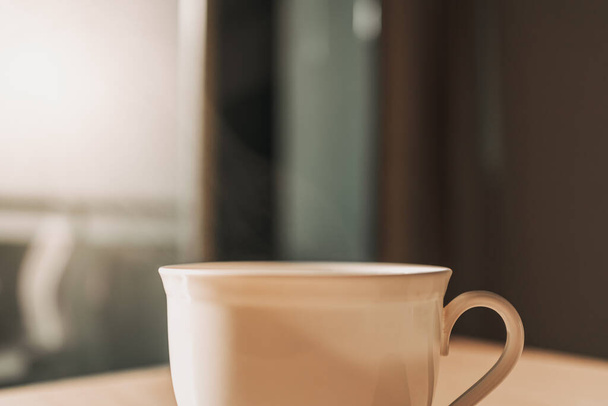 Горячая чашка напитка на столе в солнечном свете спокойного утра. - Фото, изображение