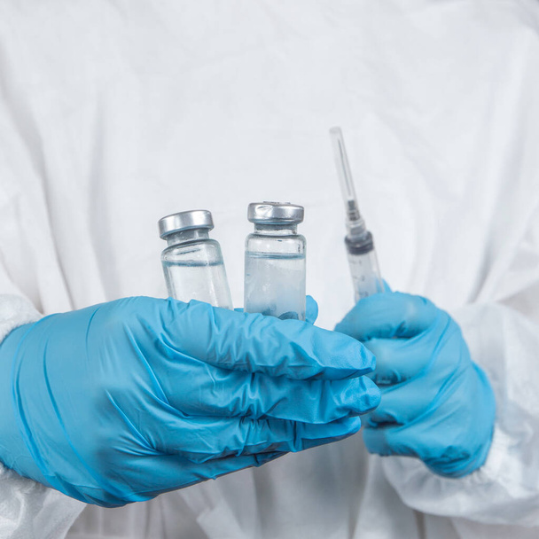 εμβολιασμός covid-19 sars-cov-2: ένας εργαζόμενος στον τομέα της υγείας με ένα εμβόλιο και μια σύριγγα στα χέρια του  - Φωτογραφία, εικόνα