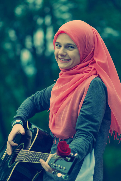 Portreit boldog muszlim lány próbál gitározni - Fotó, kép