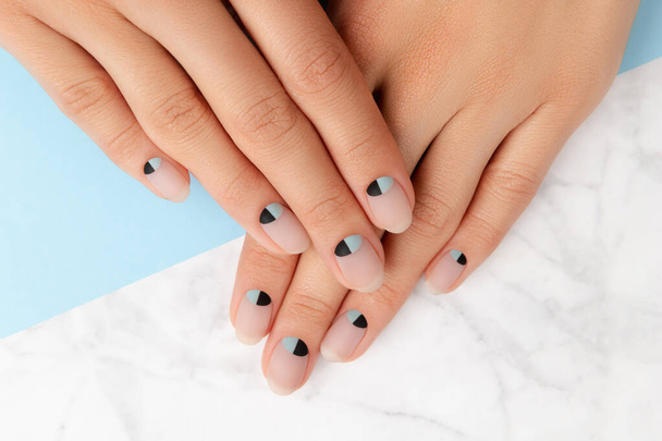 Mooie geprepareerde vrouwen handen met naakt en blauw matte nagel ontwerp - Foto, afbeelding