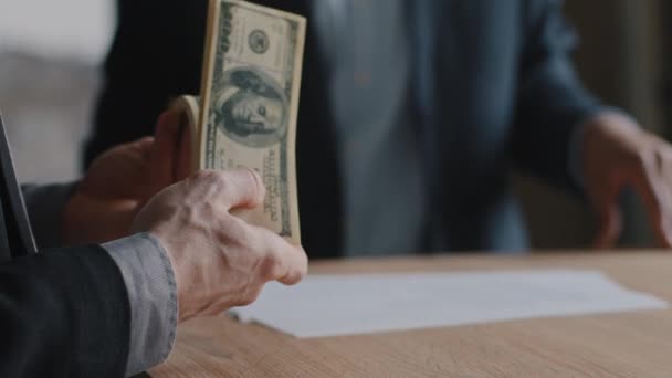 Δύο άγνωστοι μη αναγνωρίσιμοι επιχειρηματίες κάθονται στο τραπέζι του γραφείου, ανδρικά χέρια του Καυκάσιου επιτυχημένου αφεντικού κρατώντας ένα μάτσο χρήματα, μετρώντας χαρτονομίσματα δολαρίων, έννοια της οικονομικής επιτυχίας μισθό κέρδους - Πλάνα, βίντεο