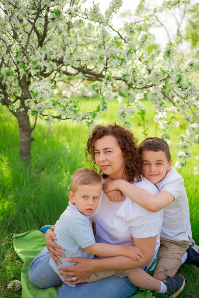 picnic. mother with sons cuddle in flowering garden. mothers day - Foto, Bild