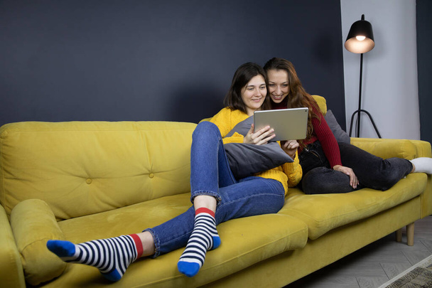 jovem casal lésbico fazer compras ou pagamentos online deitado no sofá - Foto, Imagem