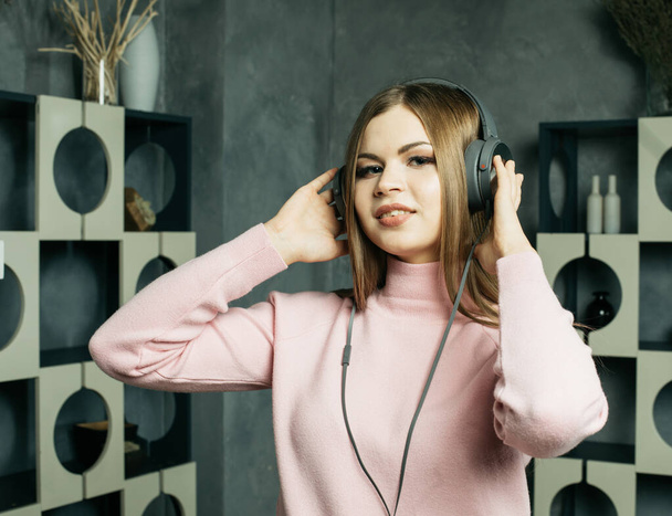 Young beautiful blond woman in casual outfit enjoying the music at home. Lifestyle, tehnology and people concept. - Foto, Imagem