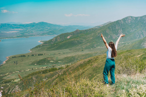 Молодая женщина стоит на фоне синего моря и гор Восточного Казахстана. - Фото, изображение