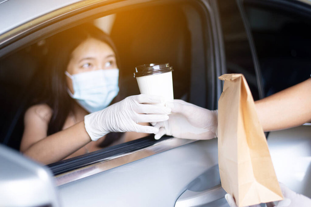 Food delivery courier give coffee cup to woman in her car,Safety food during coronavirus pandemic situation - Valokuva, kuva