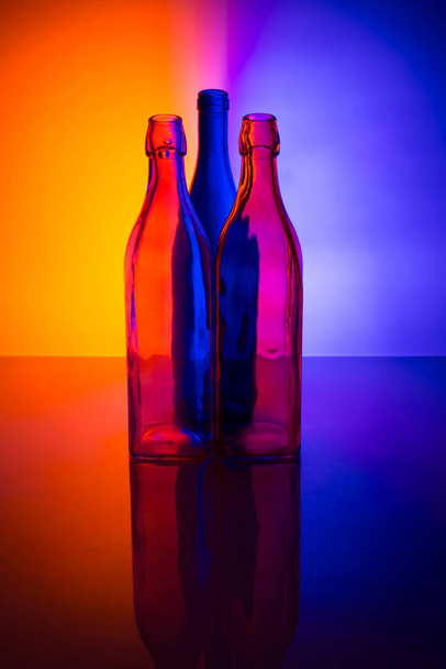 Натюрморт з кольоровими скляними пляшками на кольоровому фоні
 - Фото, зображення