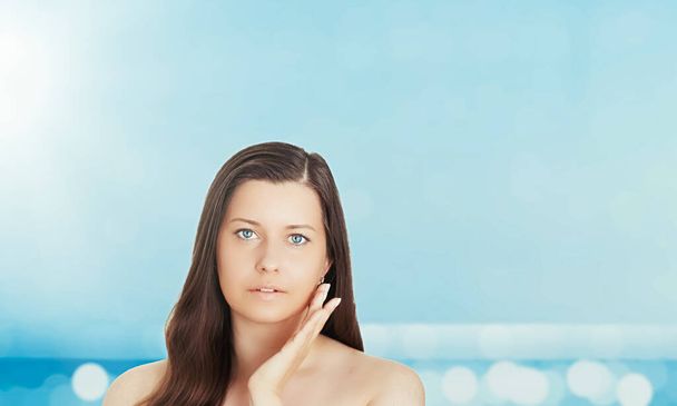 Защита от солнца и солнца летом. Портрет красивой молодой загорелой женщины, синее море и небо на заднем плане, красота, оздоровительный и туристический концепт - Фото, изображение