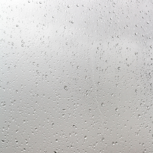 Regentropfen auf Fensterscheibe bei bewölktem Tag - Foto, Bild