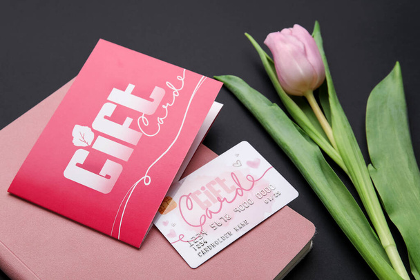 Gift card and tulip flower on dark background - Fotoğraf, Görsel