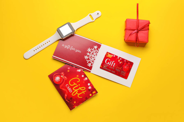 Geschenkkarte und Smartwatch auf farbigem Hintergrund - Foto, Bild