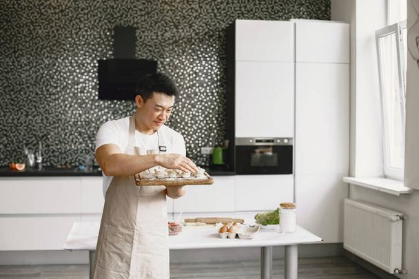 Asian man prepare dinner in a kitchen - Фото, изображение