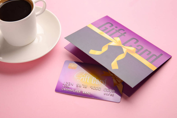 Gift card and cup of coffee on color background, closeup - Photo, Image