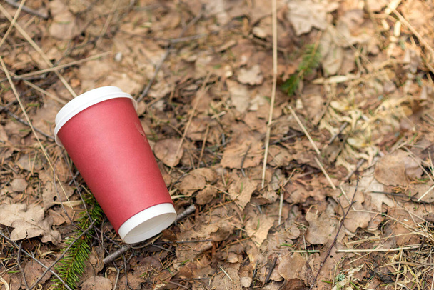 Paper cup with coffee or drink outdoor on a background of forest nature. People left behind trash. The concept of pollution of nature and the environment, background, texture.copy space. - Fotografie, Obrázek