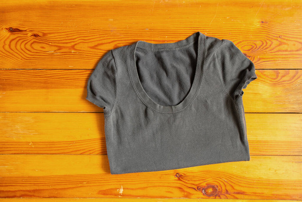 gray women's T-shirt lies on a wooden table close-up - Foto, imagen