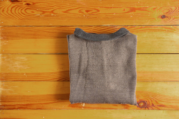 brown men's sweater folded lies on a wooden table close-up, men's clothing - 写真・画像