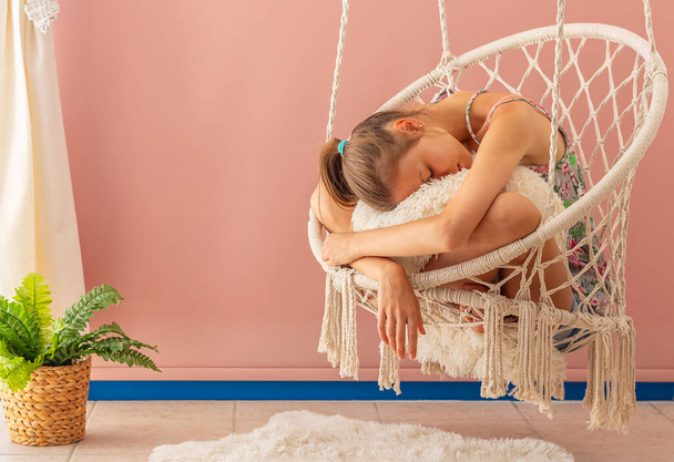 Young girl is relaxing in a hammock chair in a cozy home interior - Foto, afbeelding