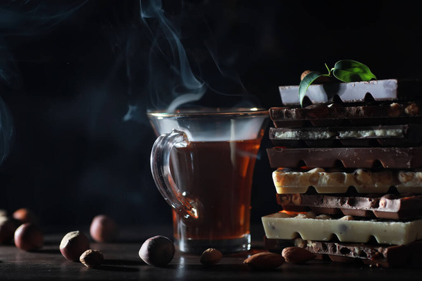 A bar of milk chocolate. Homemade milk chocolate with almonds and dried strawberries. Pieces of milk chocolate. Unlabeled milk chocolate bar.Set of chocolate with tea. - 写真・画像