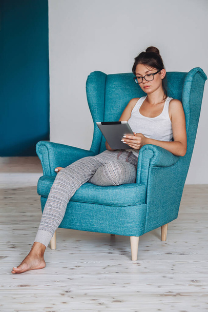 Young woman sitting in armchair and using tablet, isolated - Foto, Bild