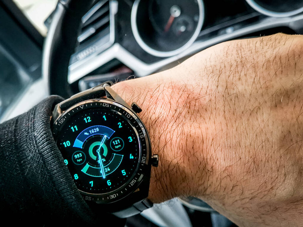 A modern black watch on a wrist of a man sitting in a car - Photo, image