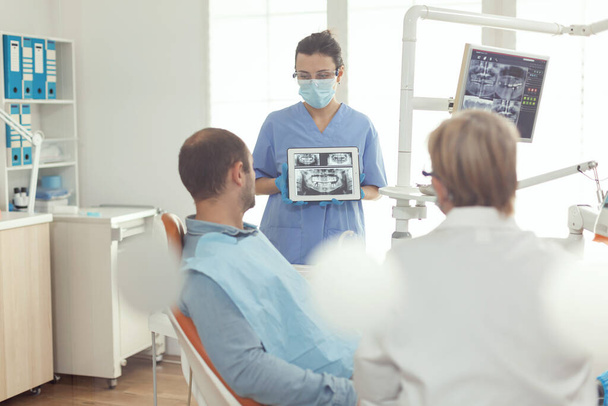 Kieferorthopädin Krankenschwester hält digitales Tablet mit Röntgenbild am Bildschirm - Foto, Bild
