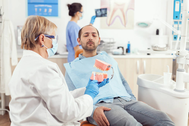 Estomatólogo senior explicando al paciente enfermo procedimiento dental - Foto, imagen