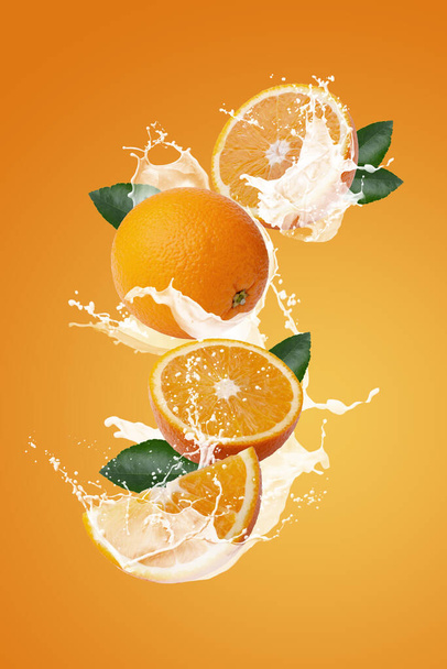 オレンジの果実とオレンジのスライス上のミルクのスプラッシングオレンジの背景に隔離されたスライス - 写真・画像
