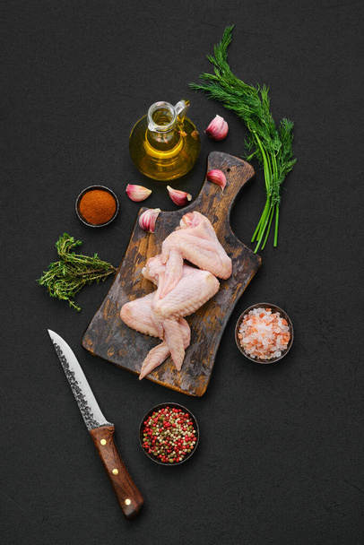 Overhead view of fresh uncooked chicken wings on wooden cutting board ready for cooking - 写真・画像