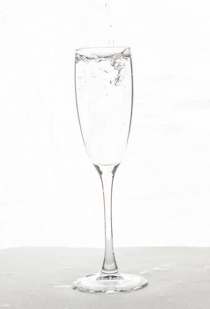 Llenar el agua de la copa de champán aislada sobre un fondo blanco - Foto, Imagen