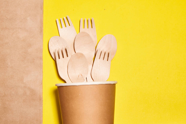 Eco friendly disposable kitchenware utensils. Wooden forks and spoons in paper cup. ecology, zero waste concept. copyspace. Layout of wooden disposable teaspoons  - Fotoğraf, Görsel