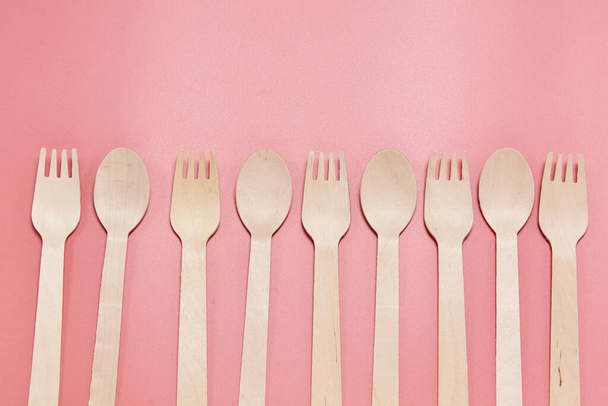 Eco-friendly disposable tableware made of bamboo wood and paper. Disposable tableware from natural materials, wooden spoon, fork, eco-friendly. Place for text. Layout of wooden disposable teaspoons  - Foto, afbeelding