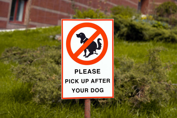 Varovné znamení: PŘESTÁVEJTE PICK PO VÁS PES. psí chůze a je zakázáno na pozadí zeleného trávníku - Fotografie, Obrázek