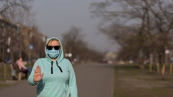 Coronavirus-Konzept Globaler Aufruf, zu Hause zu bleiben. Mädchen trägt Schutzmaske vor Krankheit und zeigt Stop-Hands-Geste zum Stopp von Coronavirus-Ausbruch. - Foto, Bild