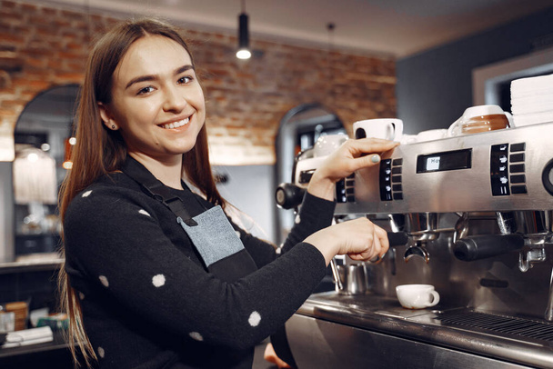 Young barista girl makes coffee and smiles - Zdjęcie, obraz