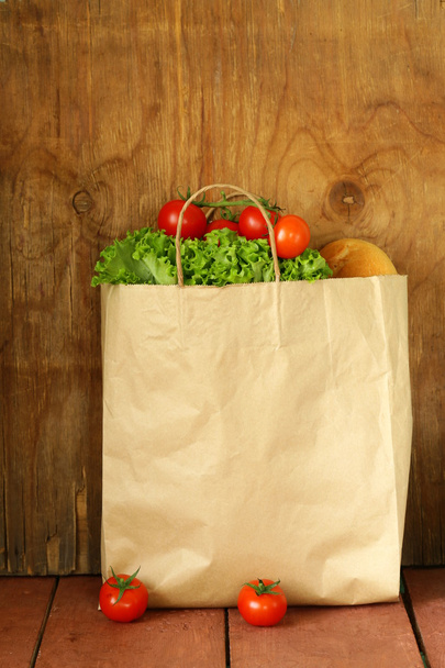 Torby papierowe z żywności, sałata, pomidory, chleb na tle drewniane - Zdjęcie, obraz