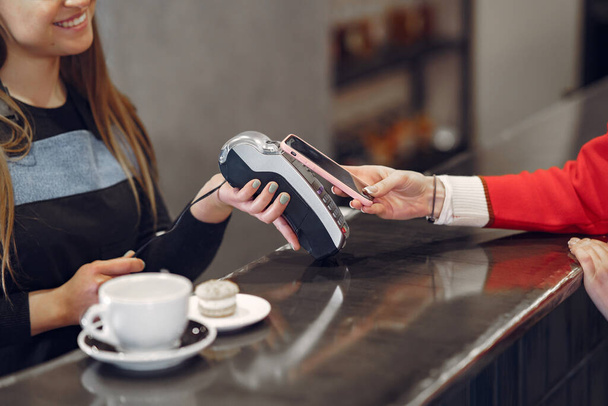 Girl paying for her latte with a smartphone by contactless PAY PASS technology - Foto, afbeelding