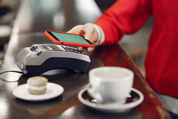 Girl paying for her latte with a smartphone by contactless PAY PASS technology - Foto, Imagen