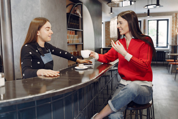 Woman sitting in a cafe and talking with barista - Photo, image