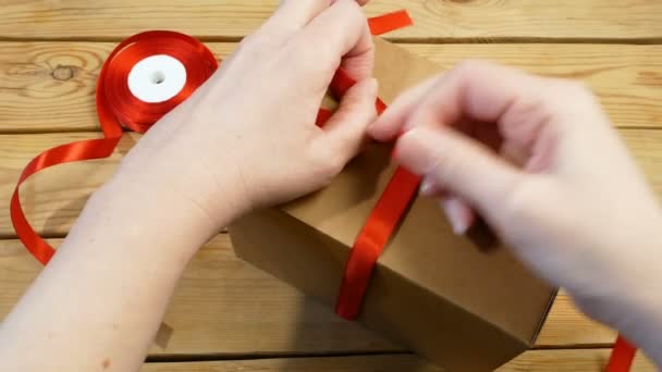 closeup πλάνα από συσκευασία δώρου με κορδέλα κόκκινο τόξο, καφέ πακέτο χαρτοκιβώτιο, έκπληξη - Πλάνα, βίντεο