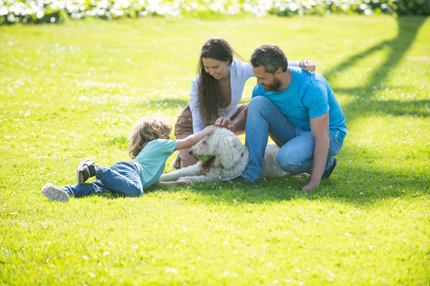 Portrait of a happy smiling family with pet dog relaxing in park. - Φωτογραφία, εικόνα