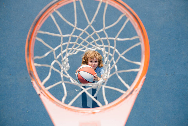 Top view of kid playing basketball holding ball with happy face. - Φωτογραφία, εικόνα