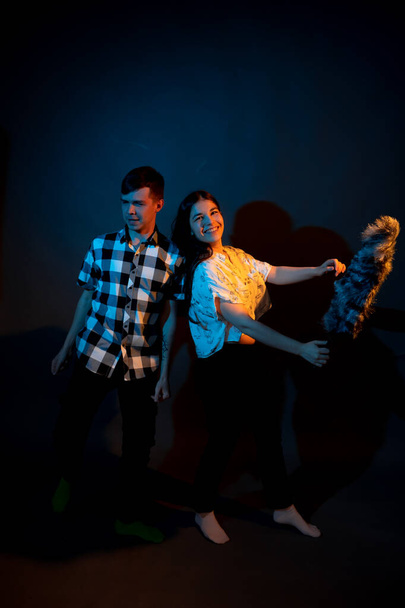 A guy in a plaid shirt and a girl with a dust brush against a dark background - Fotoğraf, Görsel